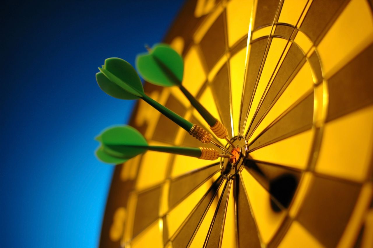 Close-up of darts hitting the bullseye on a dartboard symbolizing precision and success.